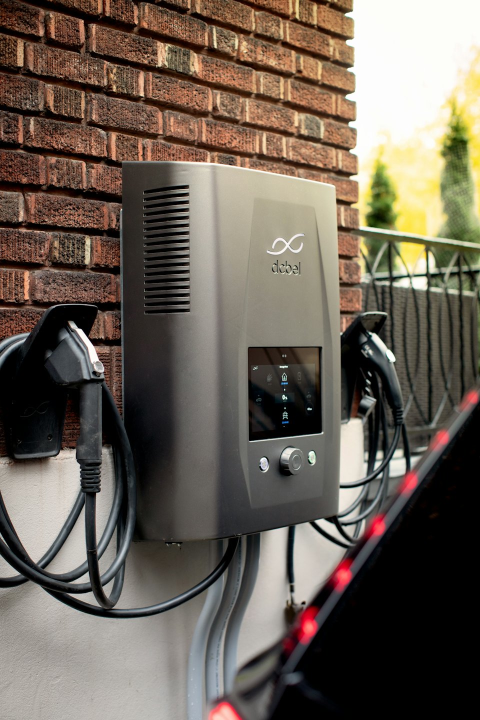 Electric car charging station on a brick wall connected to a car.