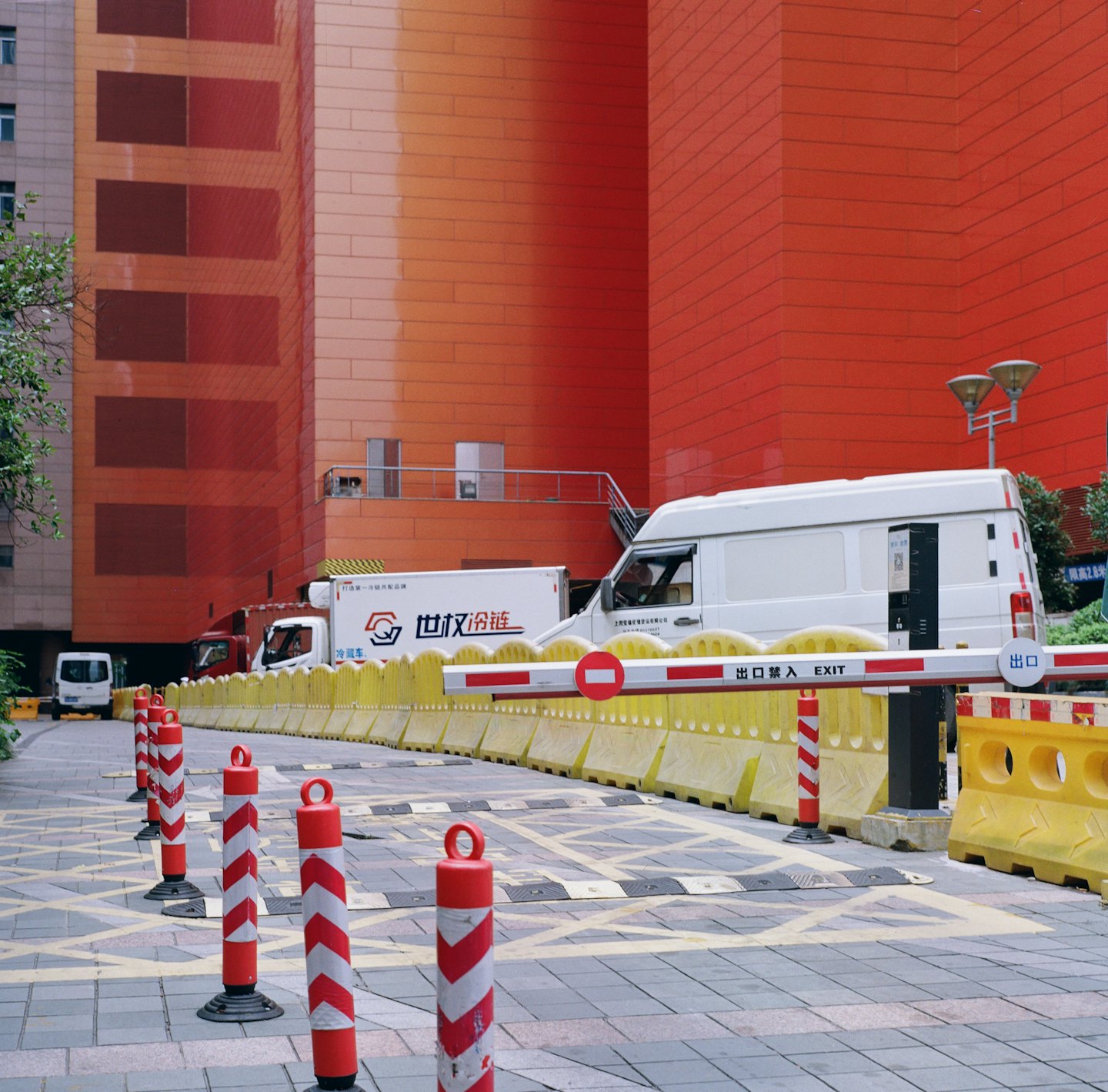 Commercial delivery vans at a logistics facility entrance with barriers.